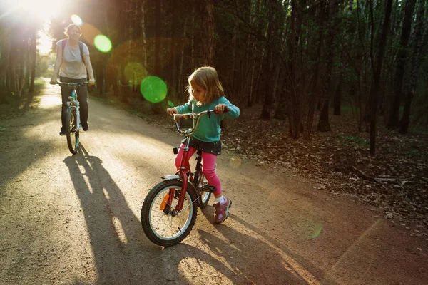 Dziewczynka z matka jazda bikes w zachód Słońca Natura — Zdjęcie stockowe