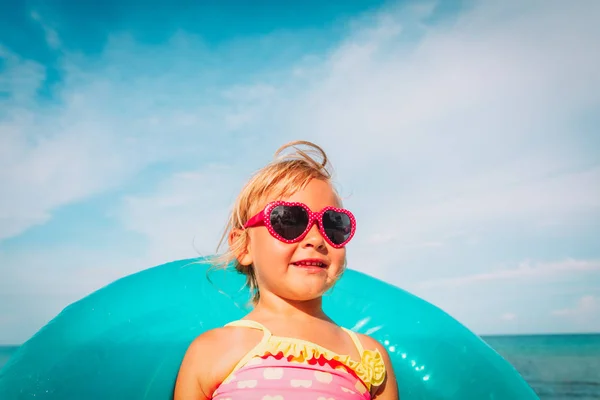 Menina bonito com brinquedo anel flutuante na praia — Fotografia de Stock