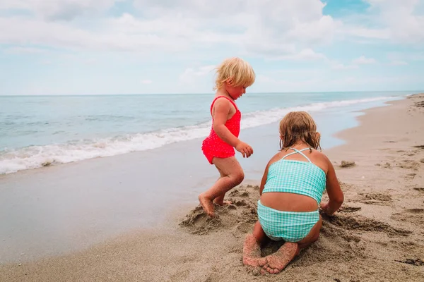 Маленькие девочки играют с песком на пляже — стоковое фото