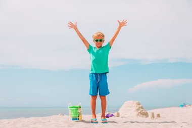 mutlu küçük çocuk tropik sahilde kum ile oynamak