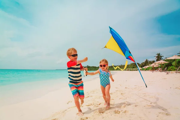 Dla dzieci - mały chłopiec i dziewczynka latający latawiec na tropikalnej plaży — Zdjęcie stockowe
