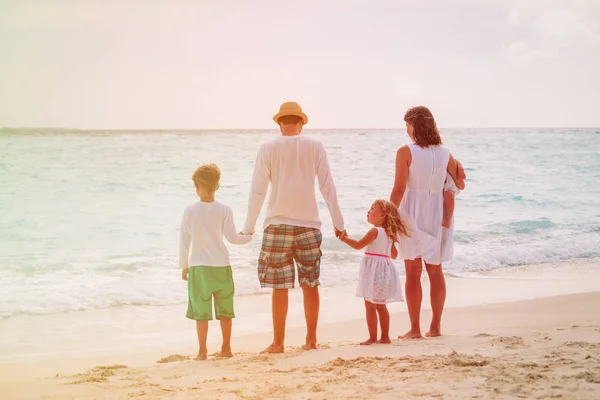 Familia feliz con los niños a pie en la playa puesta del sol — Foto de Stock