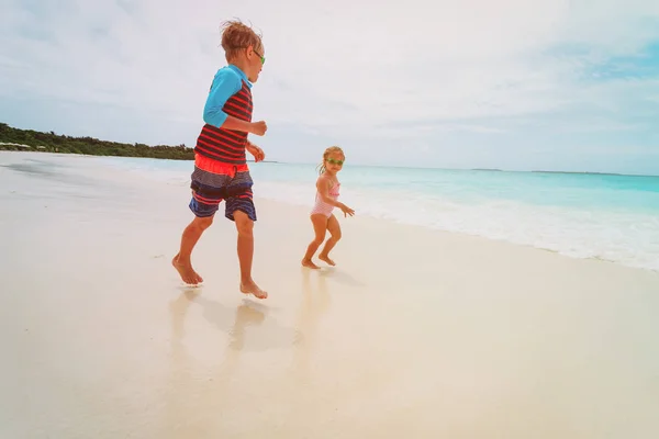 Malou holčičku a chlapce spustit hrát s vodou na pláži — Stock fotografie