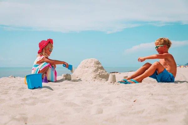 Malou holčičku a chlapce hrát s pískem na pláži — Stock fotografie