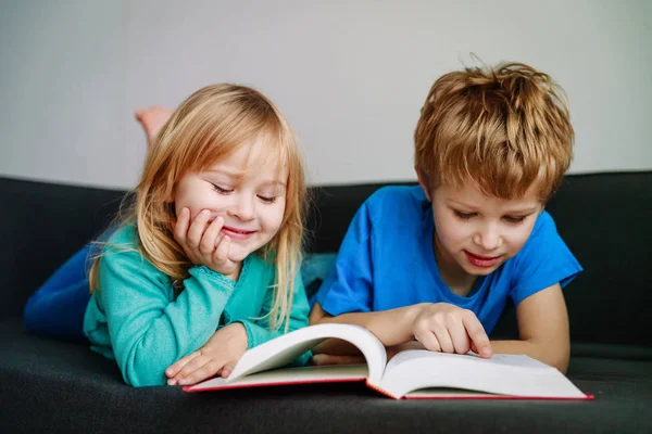 Big brother reading book to little sister, home learning — Stock Photo, Image