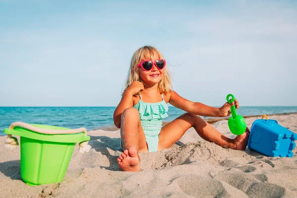 Счастливая маленькая девочка играет с песком на пляже — стоковое фото