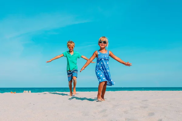 Mutlu çocuk ve kız plajda koşuyorlar. — Stok fotoğraf