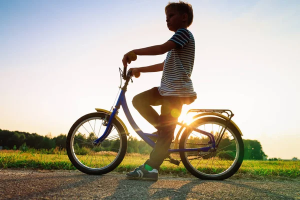 Menino andando de bicicleta ao pôr-do-sol, crianças esporte — Fotografia de Stock