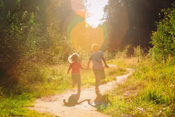 Glückliche kleine Jungen und Mädchen laufen bei Sonnenuntergang Natur — Stockfoto