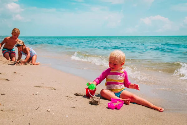 Děti - malé chlapce a dívky play s pískem na pláži — Stock fotografie