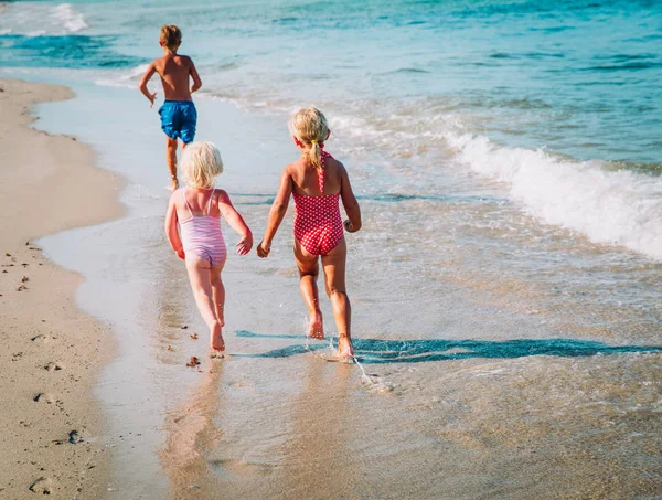 Kleine jongen en meisjes lopen spelen op strand — Stockfoto