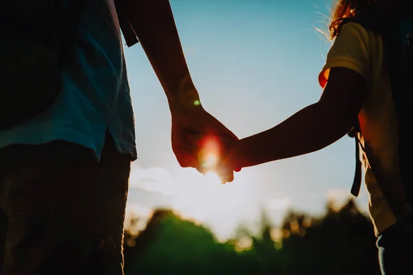 Little boy and girl with backpacks holding hands at sunset — Stock Photo, Image