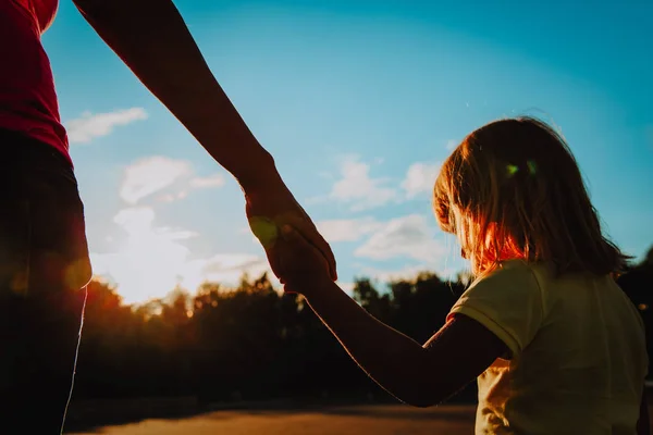 Silhueta de mãe e filha de mãos dadas ao pôr do sol — Fotografia de Stock