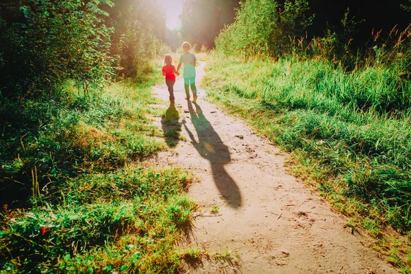 Glad liten pojke och flicka som springer i solnedgången natur — Stockfoto