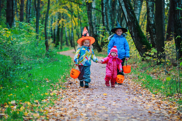 kids in halloween costume trick or treating in autumn nature