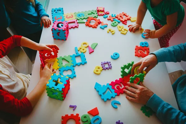 Leerkracht en kinderen spelen met nummer puzzel — Stockfoto