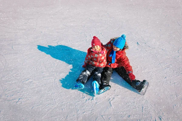 Счастливые дети - мальчик и девочка учатся кататься на коньках зимой — стоковое фото