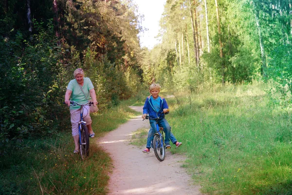 Abuela senior activa con niños montando bicicletas en la naturaleza —  Fotos de Stock