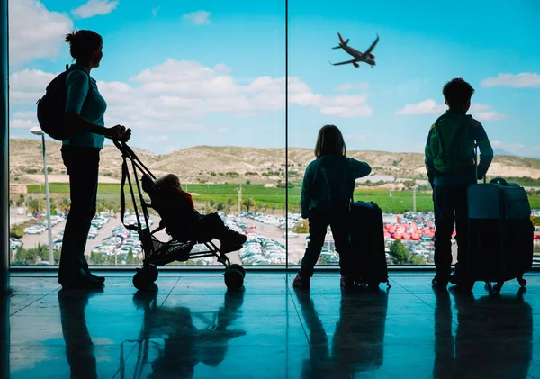 Madre con niños y equipaje mirando aviones en el aeropuerto —  Fotos de Stock