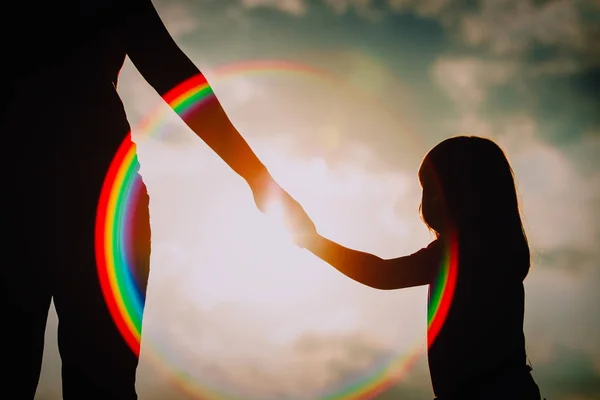 Silhueta de menina segurando a mão dos pais ao pôr do sol — Fotografia de Stock