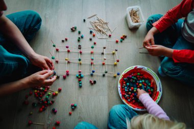 Çocuklar çubuklardan geometrik şekiller yapıyor ve hamur oynuyorlar.
