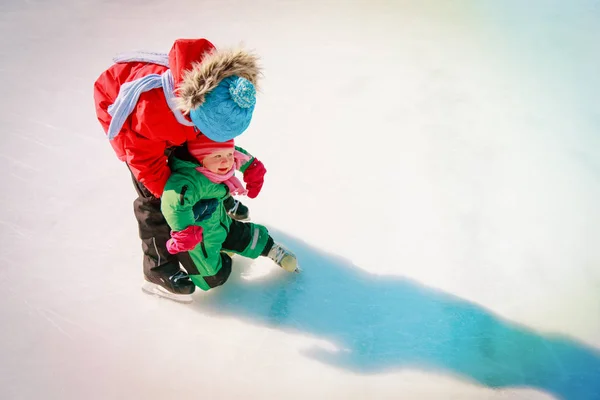 Frère enseignant à sa petite sœur à patiner en hiver — Photo