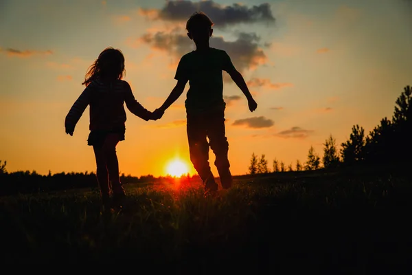 快乐的男孩和女孩的剪影奔跑戏剧在日落 — 图库照片