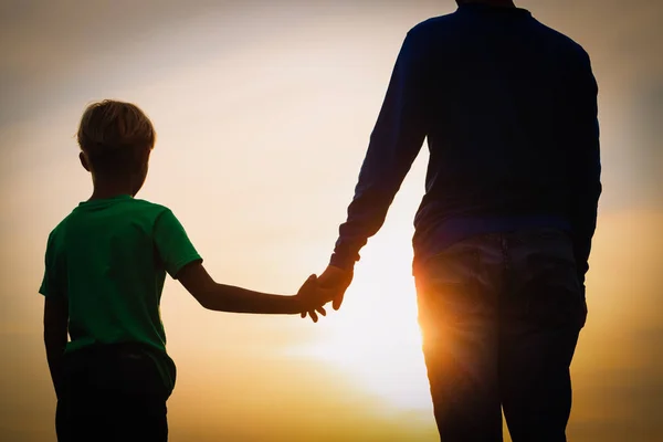 Silhouette von Vater und Sohn beim Händchenhalten bei Sonnenuntergang — Stockfoto