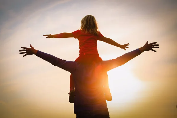 Pai e pequena filha silhuetas jogar ao pôr do sol — Fotografia de Stock