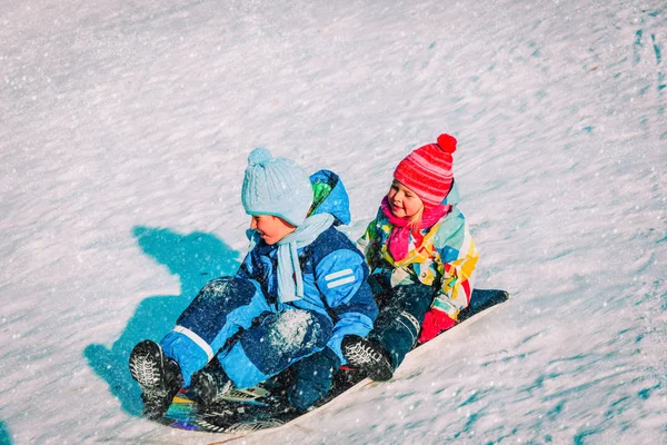 Kleine jongen en meisje dia in wintersneeuw — Stockfoto