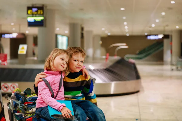 Liten pojke och flicka vänta i flygplats, sitta på bagage, familj resor — Stockfoto