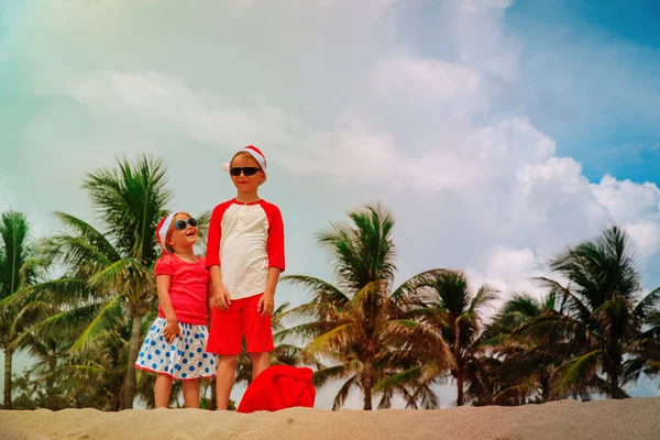 Meninos felizes... Menino e menina... a celebrar o Natal na praia tropical. — Fotografia de Stock
