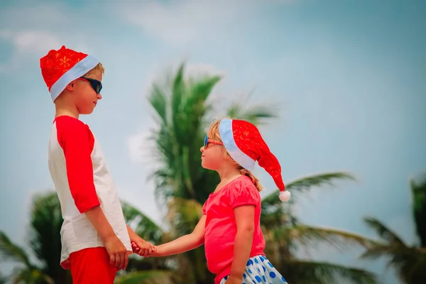 Счастливые дети маленький мальчик и девочка празднуют Рождество на тропическом пляже — стоковое фото