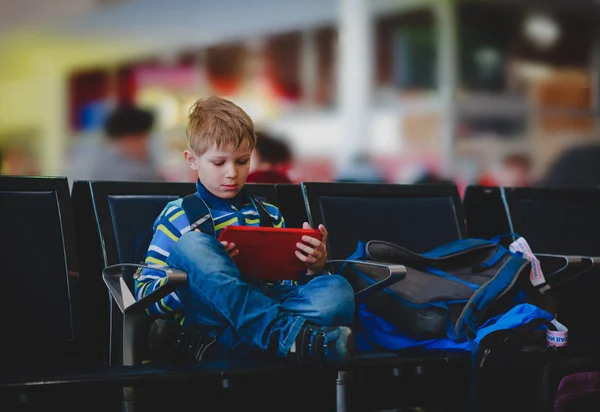 Junge schaut auf Touchpad am Flughafen — Stockfoto