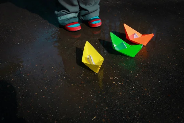 Criança brincando com barcos de papel na poça de água — Fotografia de Stock