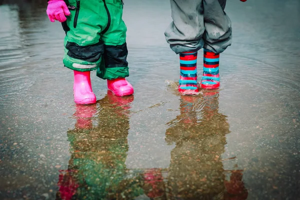 Niños en botas de goma jugando en charco de agua — Foto de Stock