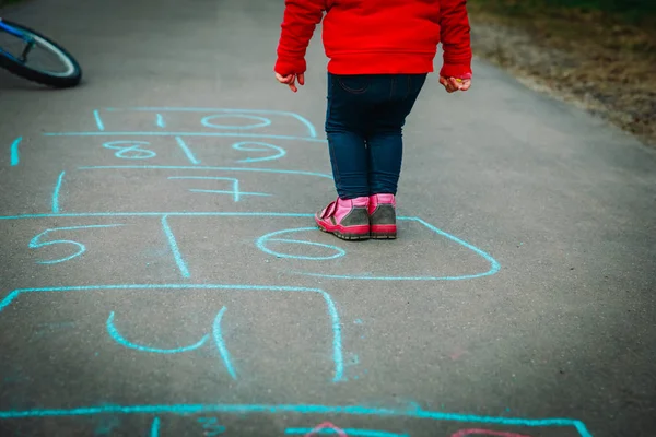 Menina jogar hopscotch no playground ao ar livre — Fotografia de Stock