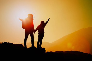 Mutlu anne ve oğlu günbatımında hiking siluetleri