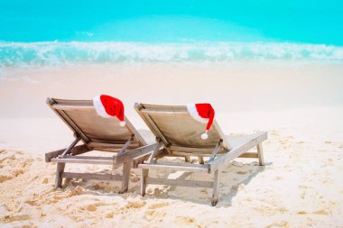 Noel plajda-sandalye salon Santa şapkalar ile denizde