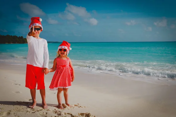 Dzieci chłopiec i dziewczynka - obchodzi Boże Narodzenie na tropikalnej plaży — Zdjęcie stockowe
