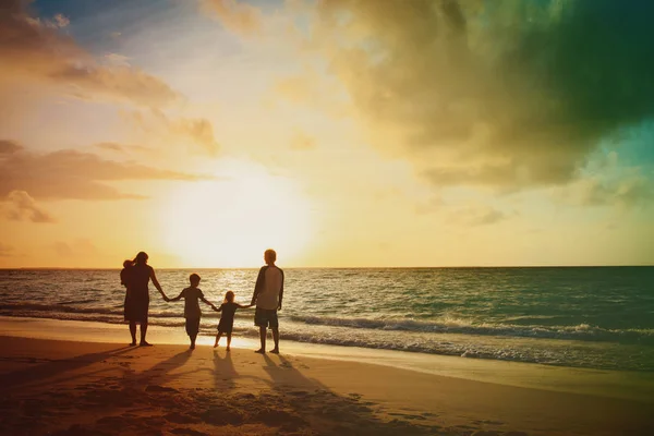 Família feliz com crianças andando na praia tropical por do sol — Fotografia de Stock