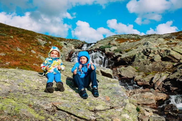 Mały chłopiec i dziewczyna cieszyć się podróż w naturze przy wodospadzie — Zdjęcie stockowe