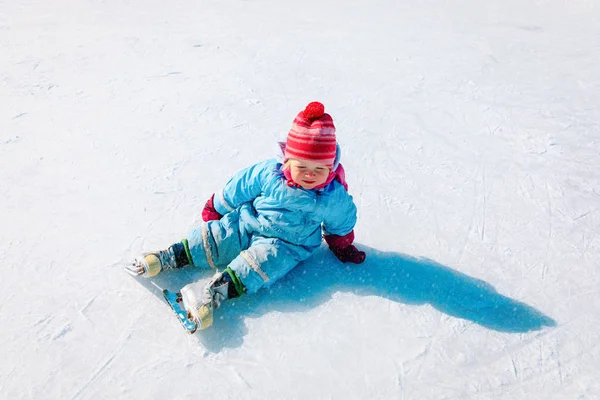 Χαριτωμένο μικρό κορίτσι που κάθεται στον πάγο με πατίνια, μαθαίνοντας πατινάζ — Φωτογραφία Αρχείου