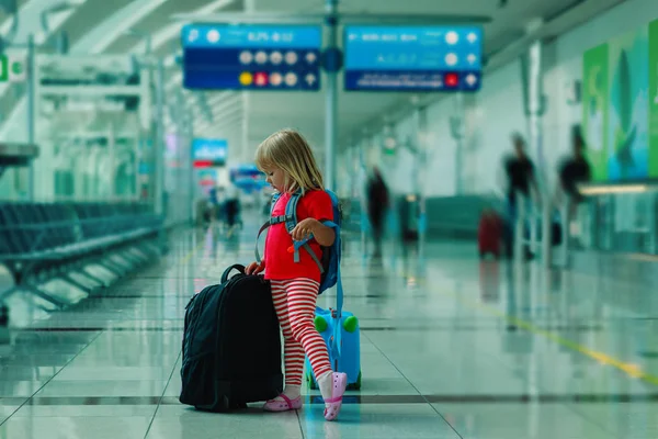 Pieni tyttö matkalaukut matkustaa lentokentällä, perheloma — kuvapankkivalokuva