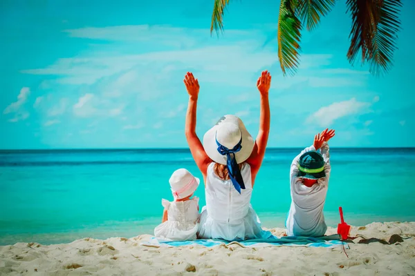 Felice madre con due bambini mani in alto sulla spiaggia — Foto Stock