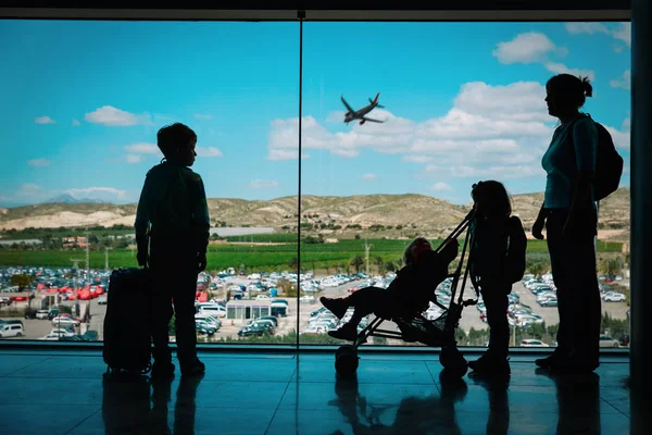 Мати з дітьми та багажем дивиться на літаки в аеропорту — стокове фото