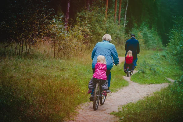 active senior grandparents with kids riding bikes in nature