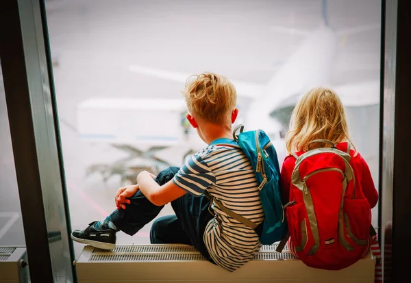 Menino e menina à espera de avião no aeroporto — Fotografia de Stock