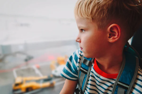 Liten pojke väntar i flygplats tittar på flygplan, familj resor — Stockfoto
