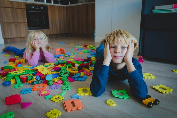 Menino e menina cansado estressado exausto com brinquedos espalhados dentro de casa — Fotografia de Stock